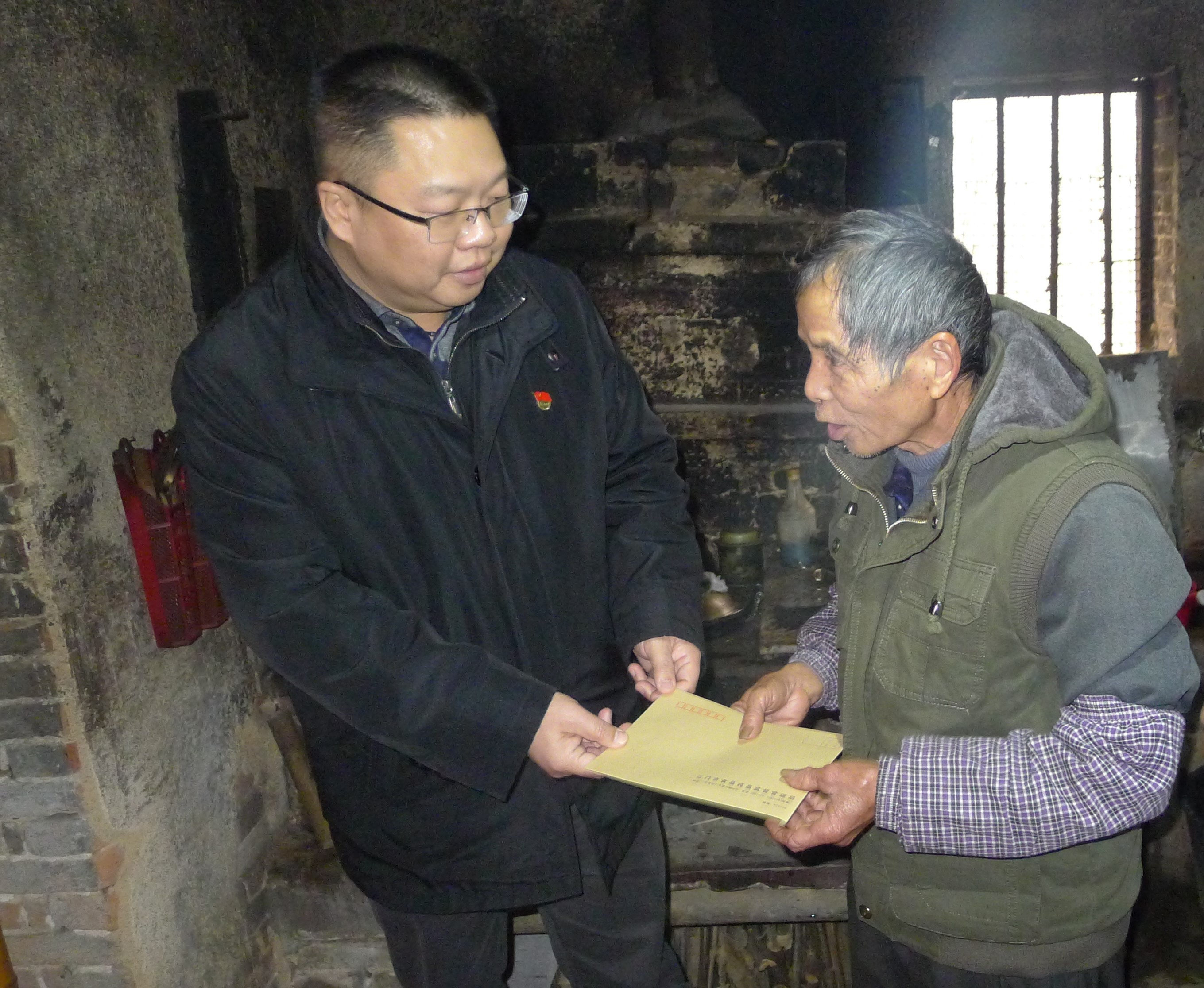 圖為：江門(mén)市食品藥品監(jiān)督管理局黨組成員、紀(jì)檢組長(zhǎng)蔣業(yè)洲向黃村村委會(huì)吳達(dá)文送上春節(jié)慰問(wèn).jpg